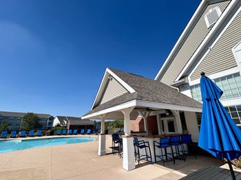A poolside bar area with a gazebo and blue umbrellas.